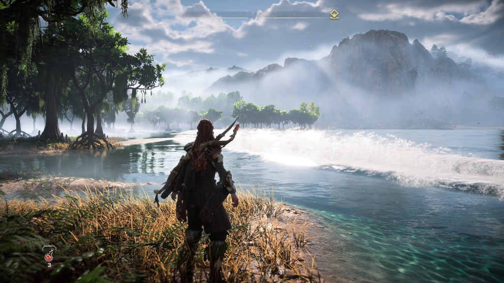Aloy standing on a beach with a forest to her left, crashing waves of azure blue water from the right and a mountain line in the background.