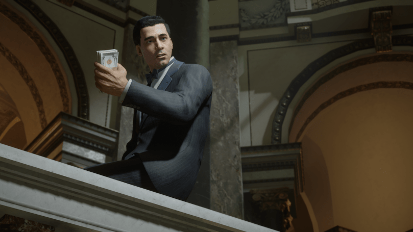 Sam sit on the railing of a museum holding several bills of money in his hand while he looks down towards Tommy at the start of the final mission.