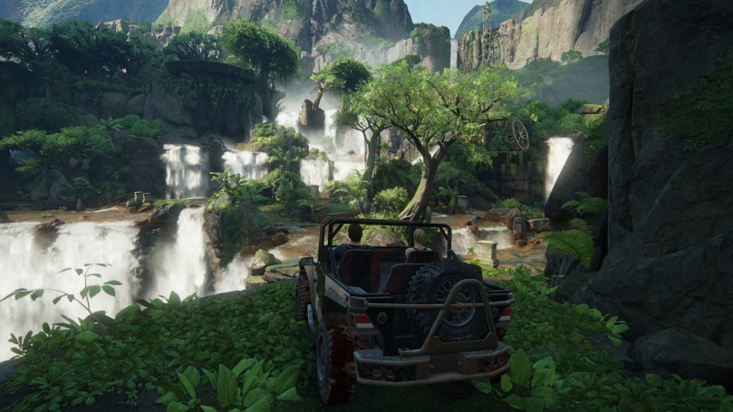 Nate and Elena are sitting in a jeep in a jungle, where several smaller waterfalls can be seen in the near distance.