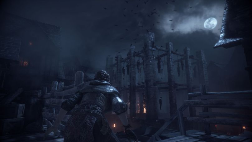 Amicia sneaking through a town at midnight. In the background is a burnt-out building used as a hanging tree full of corpses.